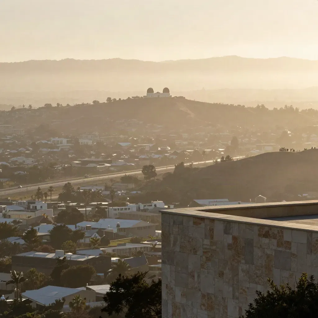 Hazy Los Angeles basin with rooftops, ridgelines, and an observatory high on the horizon.